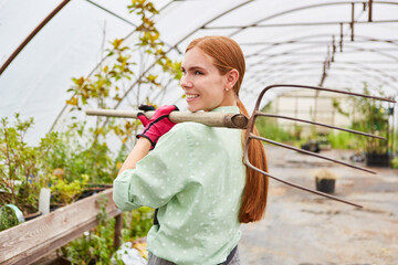 Trainee gardener with a fork in the greenhouse