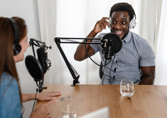 Multiracial people recording a podcast using microphone and headphones from home studio