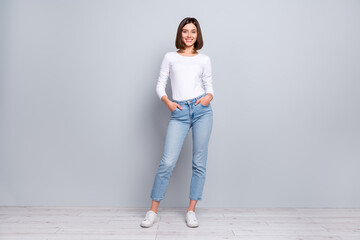 Photo of pretty charming young woman wear white outfit walking arms pockets smiling isolated...