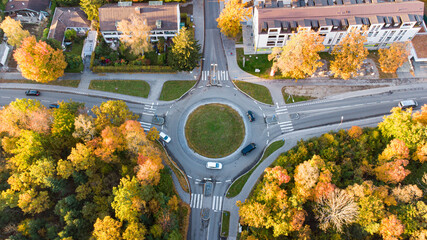 Cars driving through roundabout seen from above in the fall season - obrazy, fototapety, plakaty