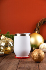 Christmas mock up of white thermo cup on wooden table with festive decorations. Golden and red Christmas colors.