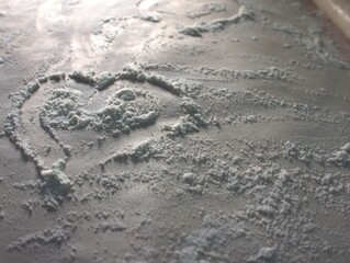 Naklejka premium Heart painted on scattered flour. Flour on paper parchment