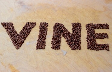 The inscription "VINE" lined with grape seeds on a wooden baking sheet. Has a double meaning: a vine and a short video on the Internet