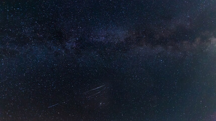 Section of night sky with Milky Way and meteor trails