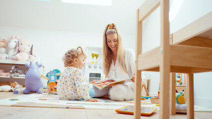 Young beautiful mother playing with her daughter at home.