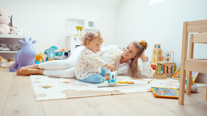 Young beautiful mother playing with her daughter at home.