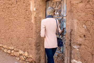 Obraz na płótnie Canvas A Western female tourist standing at the old metal door in Ushaiqer Heritage Village, Saudi Arabia. Back view.