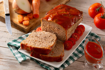 Traditional American meatloaf with ketchup on wooden table