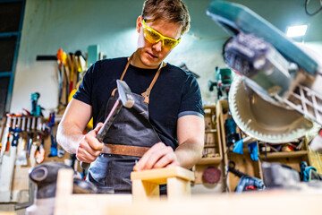 Young carpenter sawing board with circular saw