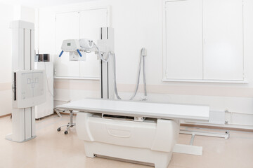 X-ray department in modern hospital. Radiology room with scan machine with empty bed. Technician...