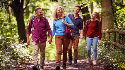 Mature And Mid Adult Couples In Countryside Hiking Along Path Through Forest Together