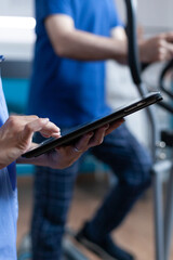 Close up of medical assistant touching tablet display to help aged patient with physical exercise for recovery. Nurse using gadget for healthcare, physiotherapy and muscle strength