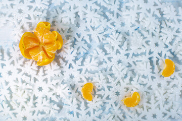 Tangerine and three peeled slices lie on white snowflakes