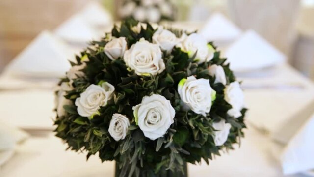 Table setting with flowers of white roses. Festive table decor. modern white interior. fake roses. Bouquet of artificial flowers