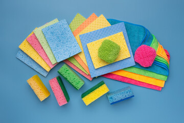 Multicolored set of rags, washcloths and sponges for cleaning various surfaces on a blue...