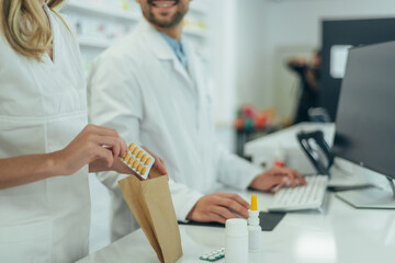 Pharmacist packing drugs in a paper bag while working in a pharmacy