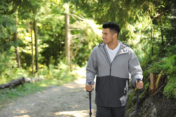 Man with trekking poles hiking in forest