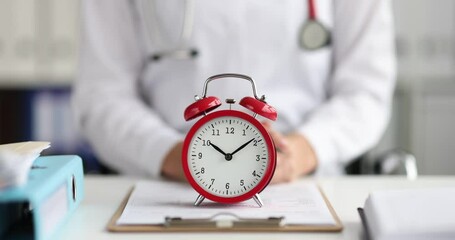 Red alarm clock standing on doctor table in clinic 4k movie slow motion