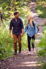 Loving Couple In Countryside Hiking Along Path Through Forest Together Holding Hands