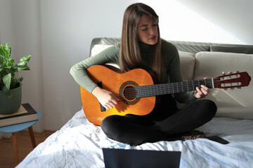 Young woman playing guitar.
Attractive young woman sits on the bed, plays acoustic guitar and...