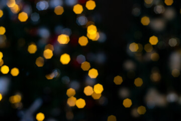 Blurred multicolored lights of a garland and branches of a Christmas tree in the foreground.Christmas and New Year background.Selective focus,copy space.