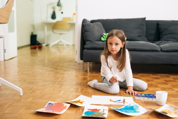 little girl painting with water colors at home
