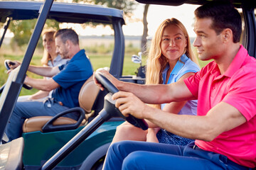 Mature And Mid Adult Couples Driving Buggies Playing Round On Golf Together