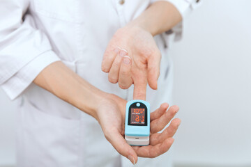 Pulse oximeter with hand of doctor isolated on white. Measuring oxygen saturation, pulse rate and oxygen levels. The concept of portable digital device to measure person's oxygen saturation.