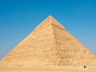 Fototapeta na wymiar Giza, Cairo, Egypt - September 30, 2021: Egyptian pyramid against the blue sky. Close-up.