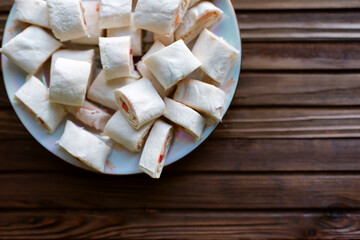 Mini roll with salmon in a pancake in a plate on a wooden background