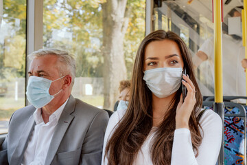 Brunette with long hair dark eyes student coming back from university by bus wearing protective...