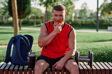 man in the park sits on a bench and eats an apple summer