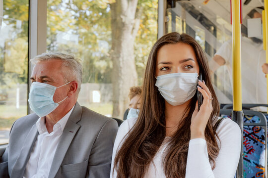 Brunette With Long Hair Dark Eyes Student Coming Back From University By Bus Wearing Protective Mask Required For Public Transport Talking On Phone Next To The Girl Is Sitting An Older Businessman