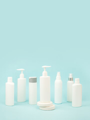 Set of white cosmetic bottles with soft shadows on light blue background. Home and beauty salon care concept, mock up, copy space, beauty industry banner, flyer, coupon, selective focus
