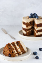 Piece of vegan carrot cake with coconut cream and nuts. Sugar, gluten and lactose free.