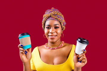 mixed race woman in yellow t-shirt and ethnic turban over head showing paper cup with african...