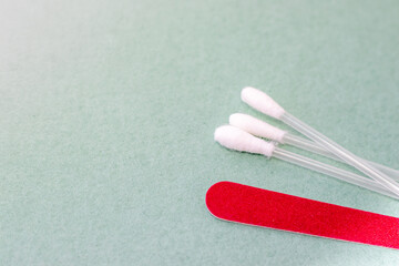 hotel bathroom accessories.white comb,nail file and ear cotton sticks buds isolated on green paper background.hotel products for daily hygiene. trip,body care. mock up free space for text.
