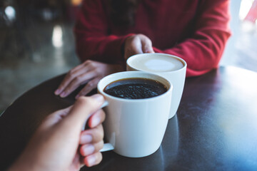 Closeup image of a man and a woman holding and clinking coffee cups together