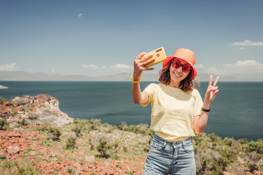 A female travel blogger takes selfies for her social networks in a picturesque Sevan Lake in Armenia