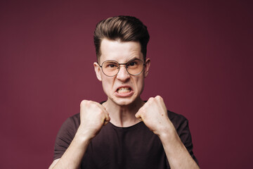 Young man holding fists up looking with determination at camera on crimson background