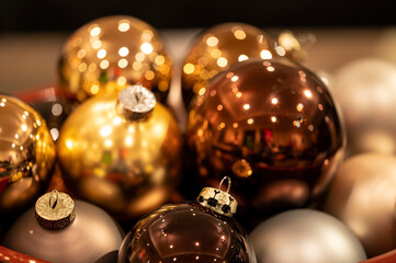 Shades of gold reflected in Christmas tree baubles, reflecting light. Shallow focus abstract seasonal image 