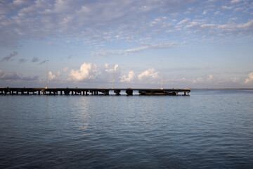 Fototapeta na wymiar The morning seascape. The pier, the sea and soft clouds above it.