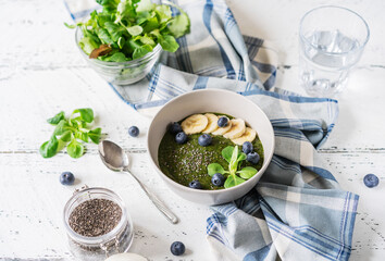 Green porridge in bawl with main ingredients: chia seeds, green, water