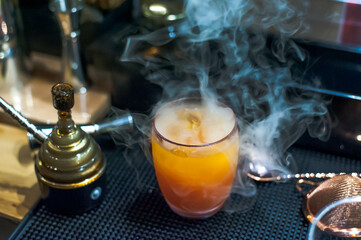 The Signature Orange color cocktail with smoke on the counter bar in Bangkok Thailand