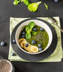 Green porridge in bawl on the black background with napkin
