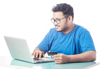 happy young man making online transaction using debit card and laptop