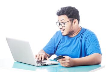 shocking man using credit card for online transaction and looking at laptop screen