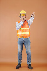Head engineer in orange vest and hardhat walking on walkie-talkie when managing work at...
