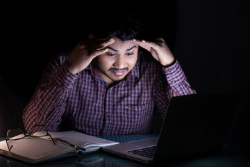 frustrated business man feeling tensed and headache while working on laptop at late night