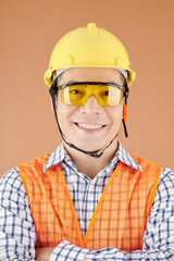 Smiling young construction site worker in hardhat and protective goggles looking at camera